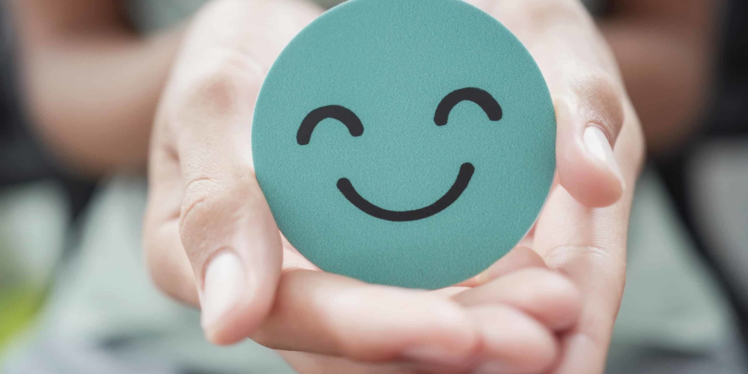 Hands holding green happy smile face paper cut, good feedback rating,think positive, customer review, assessment, child wellness,world mental health day, Compliment Day